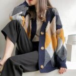 Photo d'une femme assise portant un gilet chaud boutonné avec des motifs losanges bleu, rose et jaune