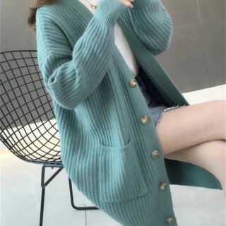 Gilet long vert porté par une femme assise sur une chaise