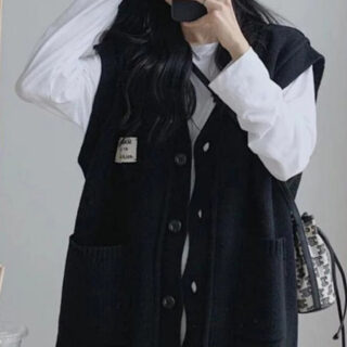 Une femme qui porte un grand gilet bleu fermé par des gros boutons.