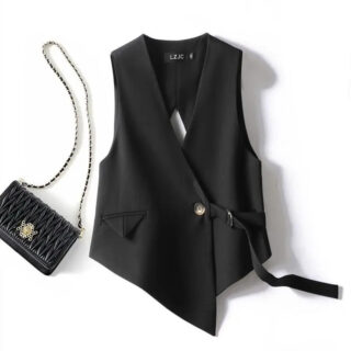 Sur fond blanc, on voit un gilet de costume noir asymétrique pour femme, près d'un petit sac à main noir avec une chaîne.