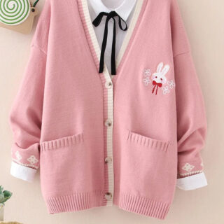 Gilet rose avec un lapin brodé en haut à gauche avec poches et boutonnière blanche. Porté avec un chemisier blanc