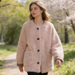 Une femme portant un gilet moumoute boutonné à col rond pour femme en se baladant dans un parc.