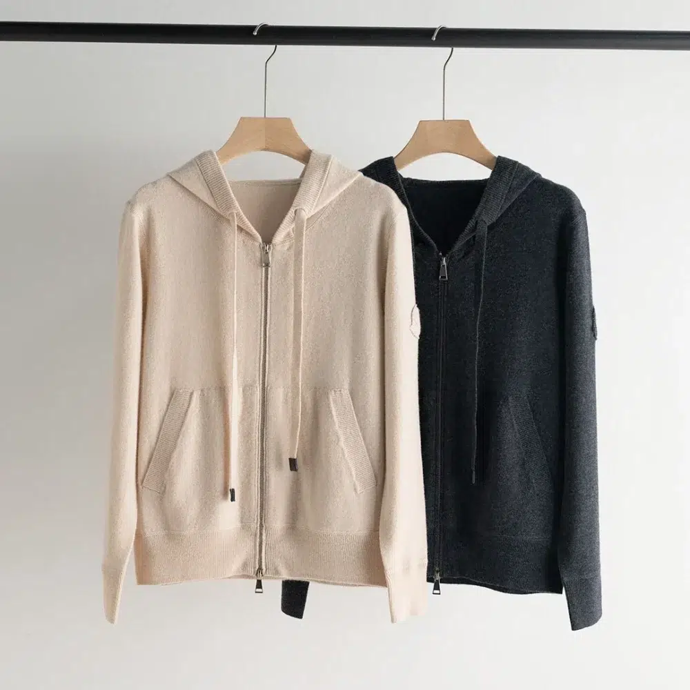 Photo de deux gilets zippés fermés à capuche en cachemire sur cintres