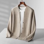 Photo d'un Gilet chaud en cachemire beige avec un col cassé, par dessus un t-shirt blanc sur un cintre sur fond gris