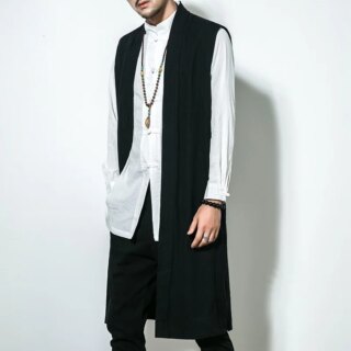 Homme portant un gilet long noir sur fond blanc.