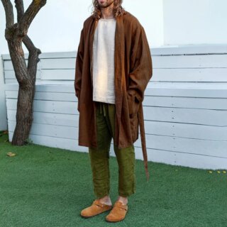 Homme portant un gilet mi-long marron avec une ceinture.
