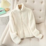 Photo d'un gilet en moumoute blanc zippé sur un cintre accroché à un canapé