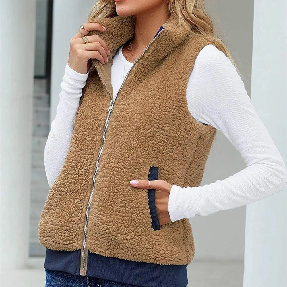 Gilet moumoute zippé sans manches Photo d'une femme portant un gilet en moumoute zippé marron sans manches avec un main dans la poche et une main qui tient le col de la veste, elle porte un t-shirt à manches longues blanc en dessous et un jean