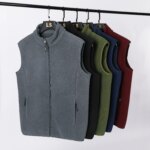 Photo de plusieurs gilet polaire sans manches suspendu à des cintres sur un portant, sur fond gris