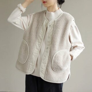 Un femme porte un gilet sans manche beige et un pantalon noir