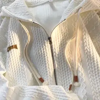 Photo d'un gilet blanc zippé à capuche avec double cordon de serrage et tissu style tricot