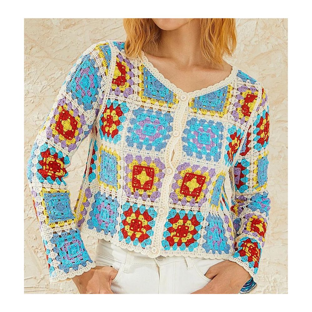 on voit sur un fond beige le buste d'une femme qui porte un gilet bohème avec motifs colorés bleus et rouges