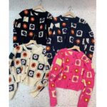 on voit sur le sol 4 gilet en crochet à motifs fleuris de différentes couleurs, rose bleu noir et blanc