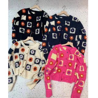 on voit sur le sol 4 gilet en crochet à motifs fleuris de différentes couleurs, rose bleu noir et blanc