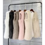 on voit devant un mur gris et sur un portant plusieurs gilet sans manches en fausse fourrure pour femme de différentes couleurs gris rose noir blanc