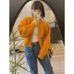 on voit une femme portant un gilet cardigan zippé coloré pour femme, il est orange