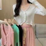 on voit une jeune femme portant un gilet court et léger rose avec des bords arrondis pour femme elle porte plusieurs gilets sur son bras