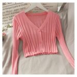 on voit posé sur un tissu beige un gilet léger court avec un col en V pour femme, il est de couleur rose