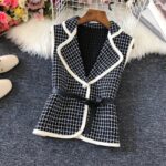 Un gilet sans manches vintage à carreaux noir et blanc posé sur un sol gris foncé