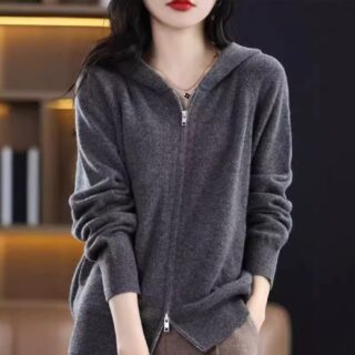 Gilet gris foncé avec capuche pour femme, style décontracté, avec une fermeture zippée. Il est porté par une femme brune