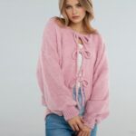 Femme portant un gilet court à manches ballon avec 3 nœuds sur le devant