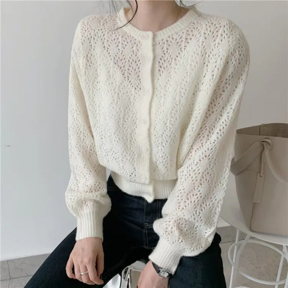 Gilet court ajouré en tricot blanc, manches longues, col rond, porté avec un pantalon noir