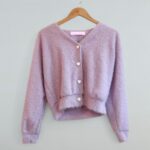 Gilet doux violet pour femme à boutons cœur, manches longues, coupe courte, vu de face sur fond neutre.