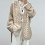 Gilet grosse maille en laine biege pour femme porté avec un look décontracté.