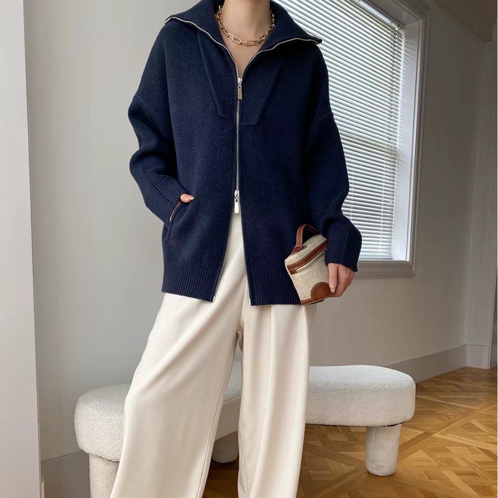 Gilet zippé oversize femme décontracté Femme portant un gilet zippé oversize en laine, coupe ample et décontractée bleu foncé, avec un pantalon blanc.