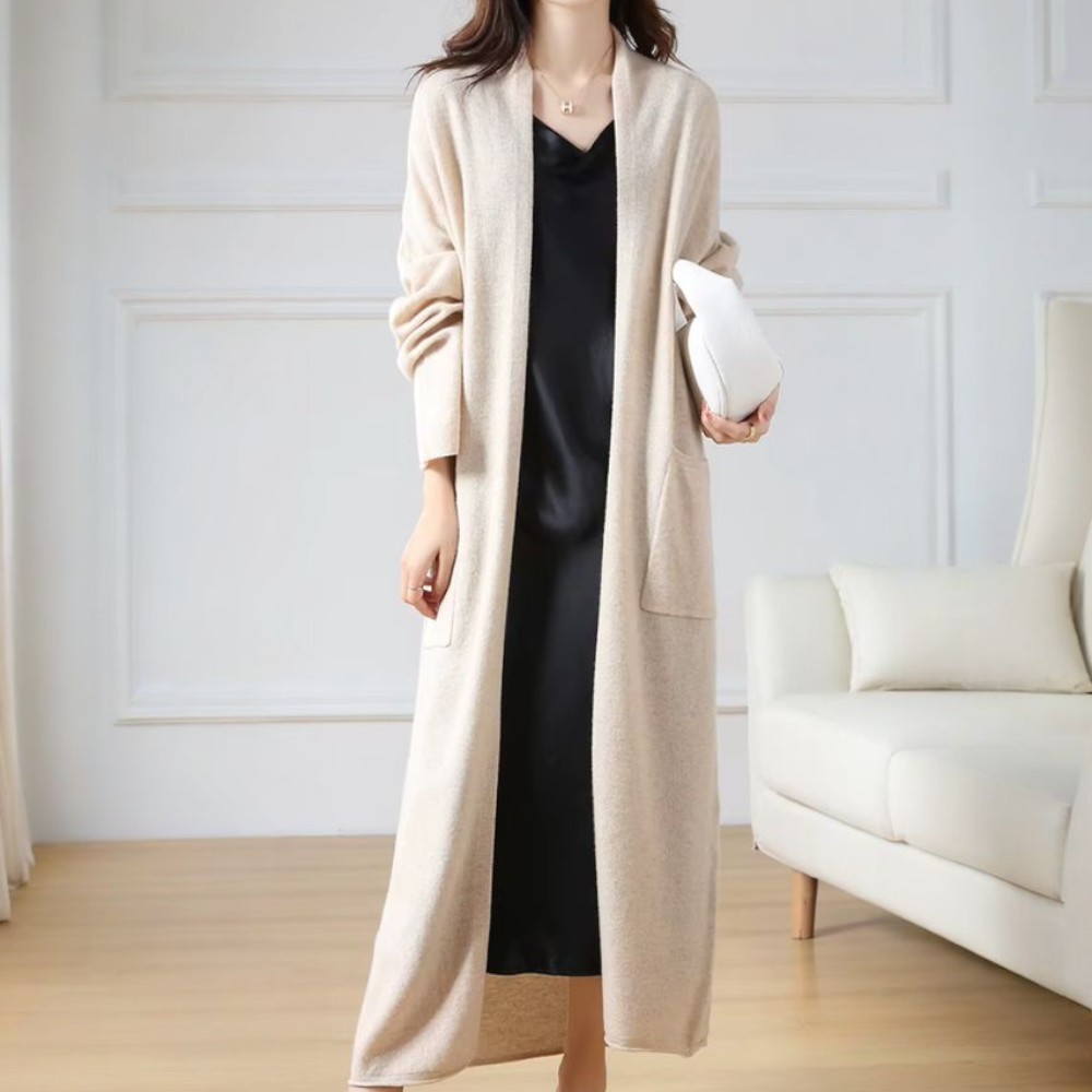 Femme portant un gilet long en maille fine légère, coupe fluide, coloris beige.